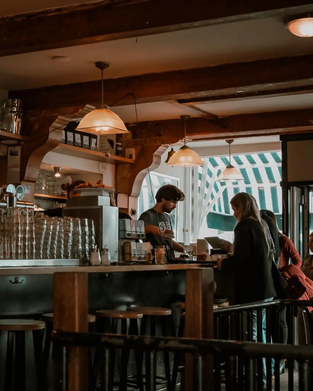 Un bar con su barra y clientes de pie.