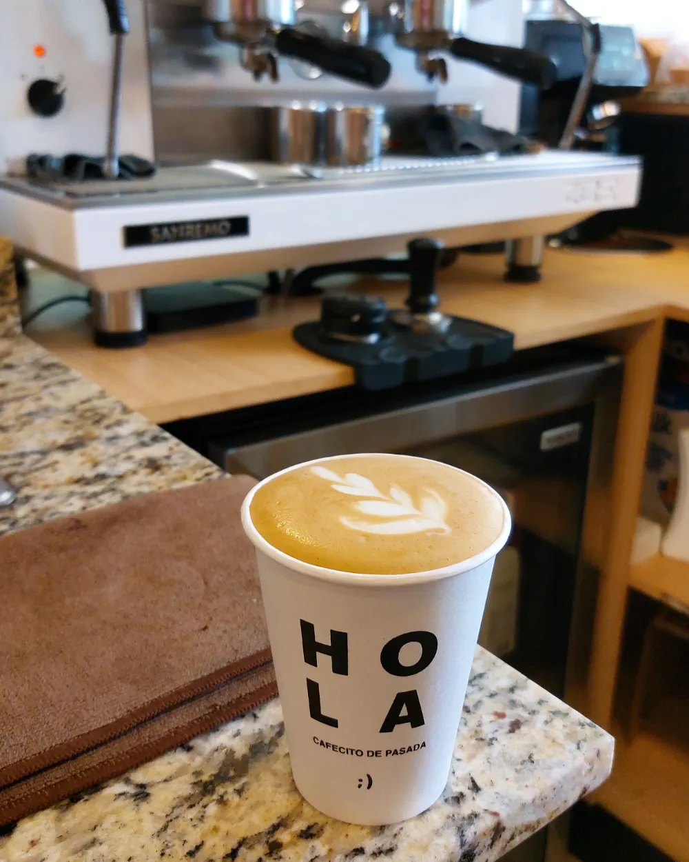 Un latte con arte en la espuma junto a la máquina de espresso.