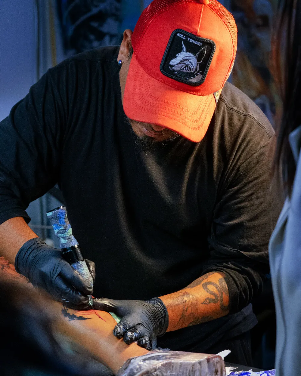 Un artista tatuando el brazo de un cliente.