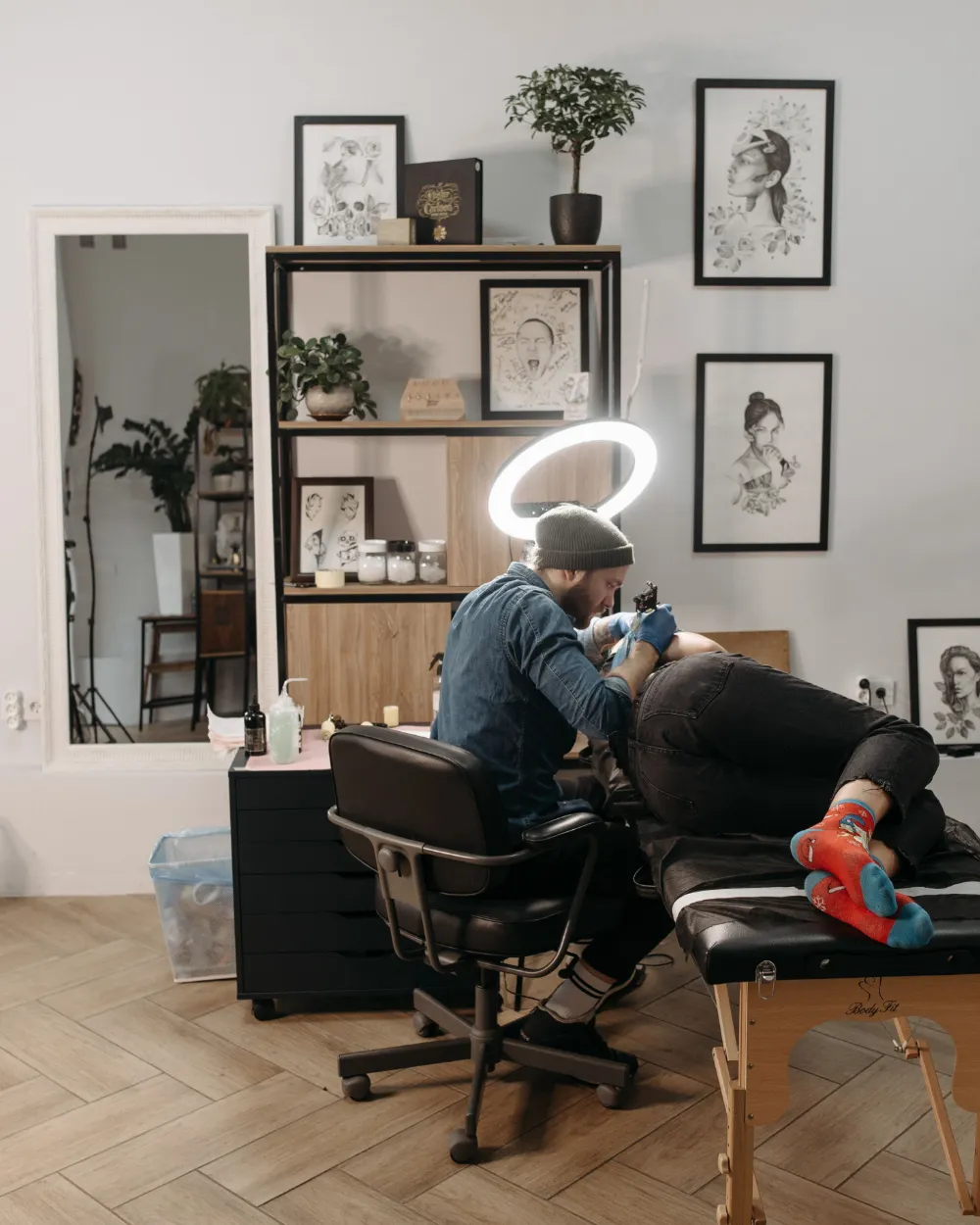 Un estudio de tatuajes con el artista trabajando en la camilla.