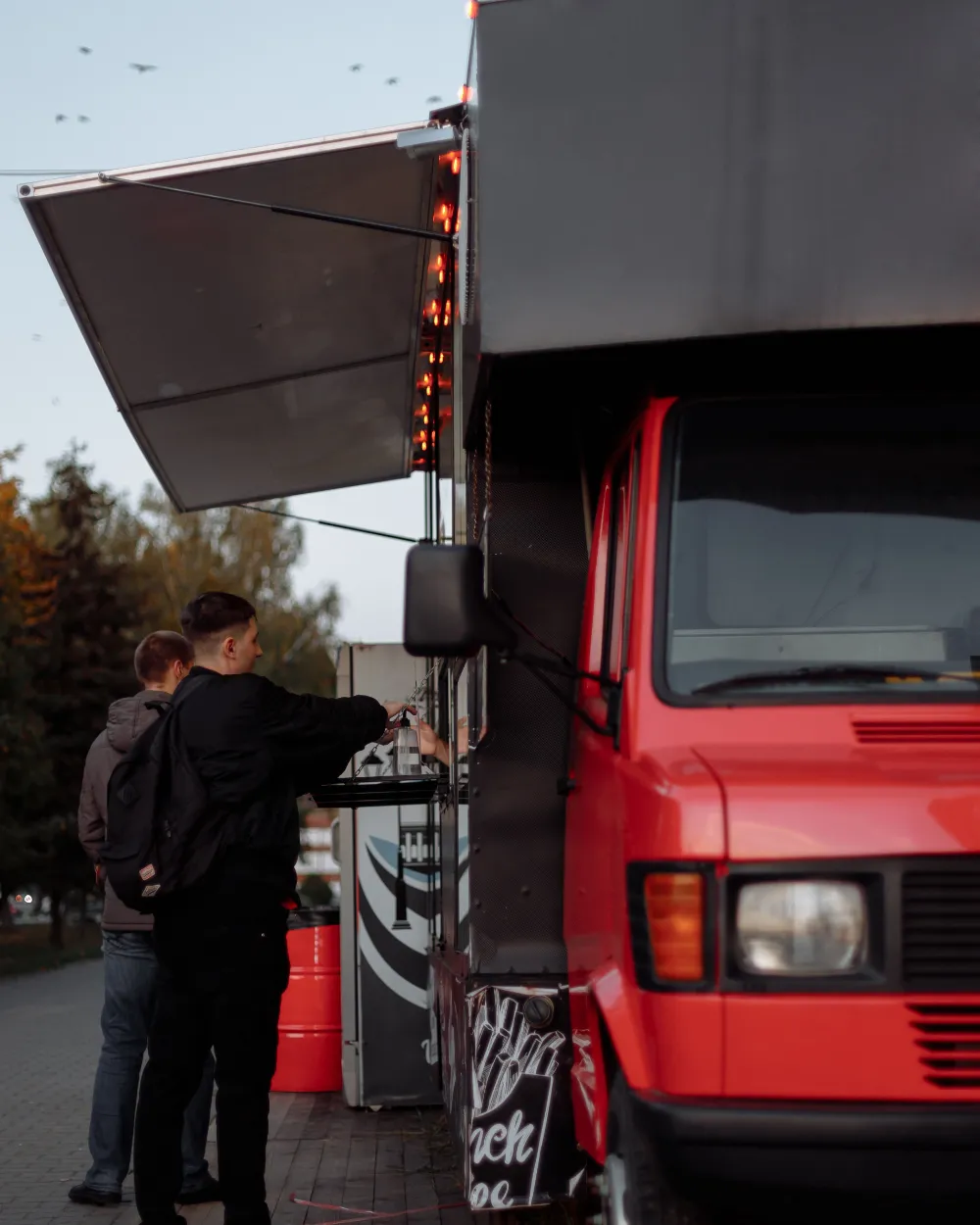 Clientes pidiendo en la ventanilla de un food truck.