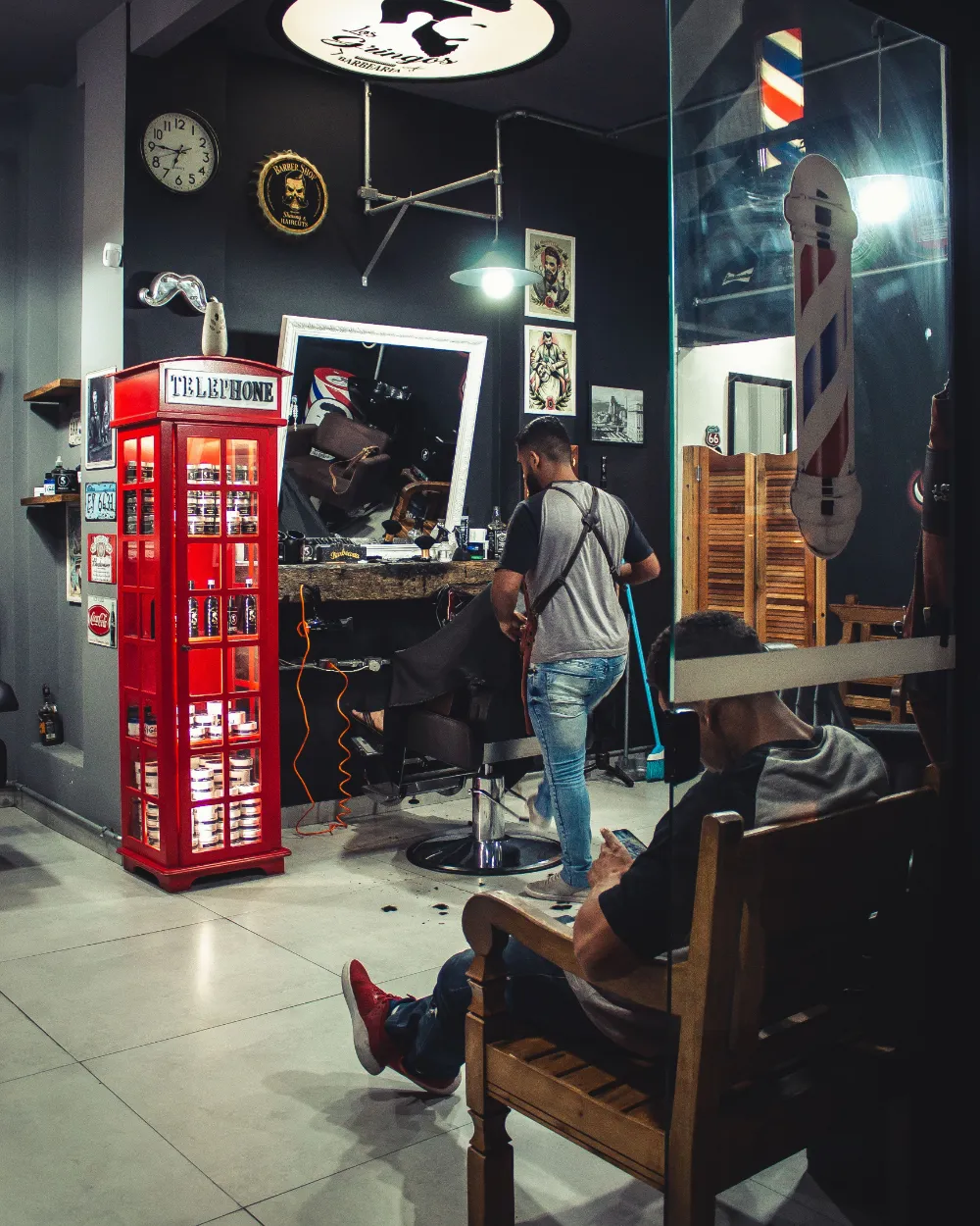 Una barbería con clientes y barberos trabajando.